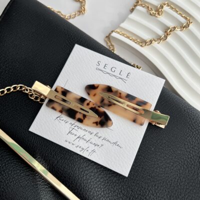 Makiažo plaukų segtukai įsegti baltoje kortelėje. segtukų paviršius tigrinių raštų