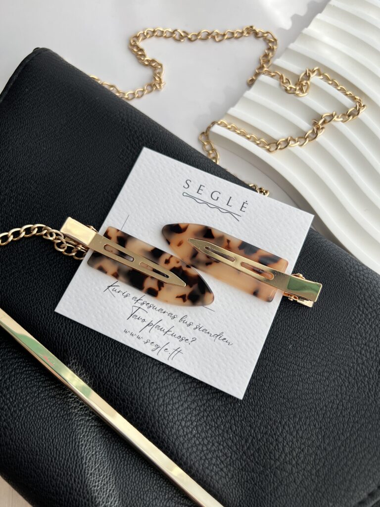 Makiažo plaukų segtukai įsegti baltoje kortelėje. segtukų paviršius tigrinių raštų