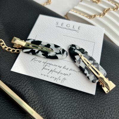 Baltų ir juodų spalvų makiažo plaukų segtukai padėti ant baltos kortelės