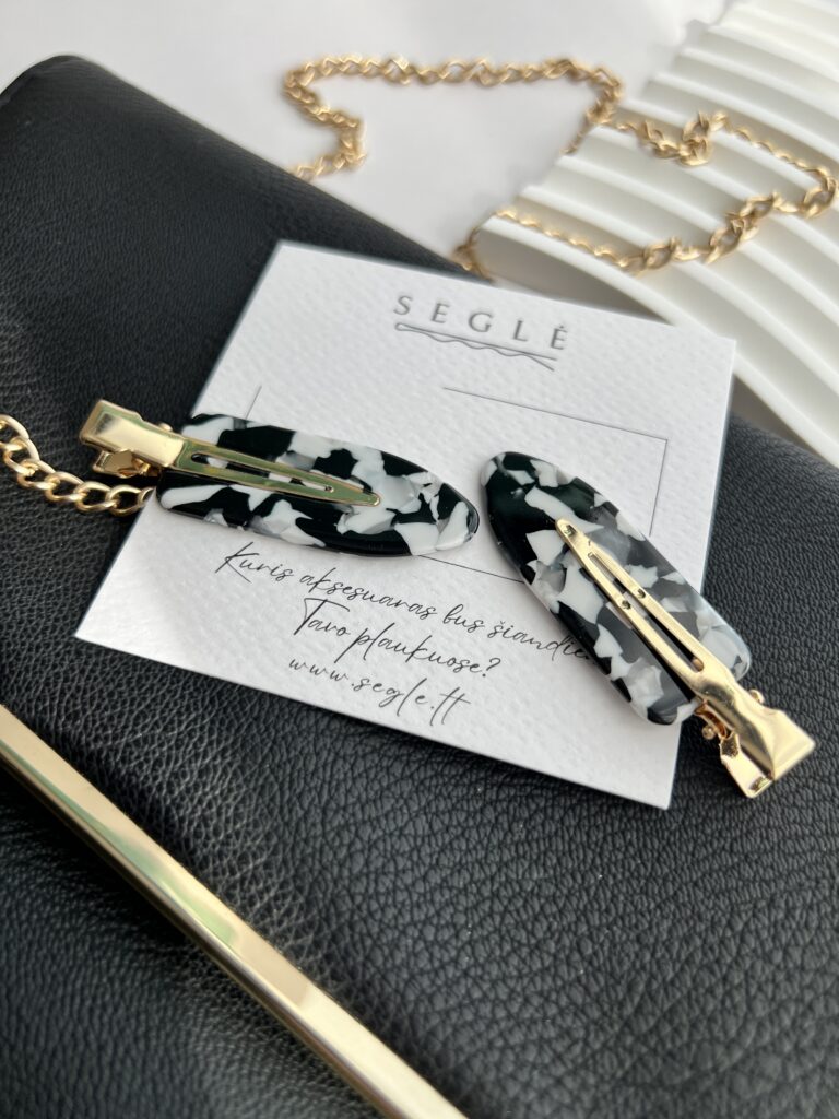 Baltų ir juodų spalvų makiažo plaukų segtukai padėti ant baltos kortelės