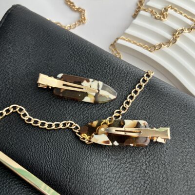 Rudų ir baltų spalvų makiažo plaukų segtukai padėti ant juodos delninukės