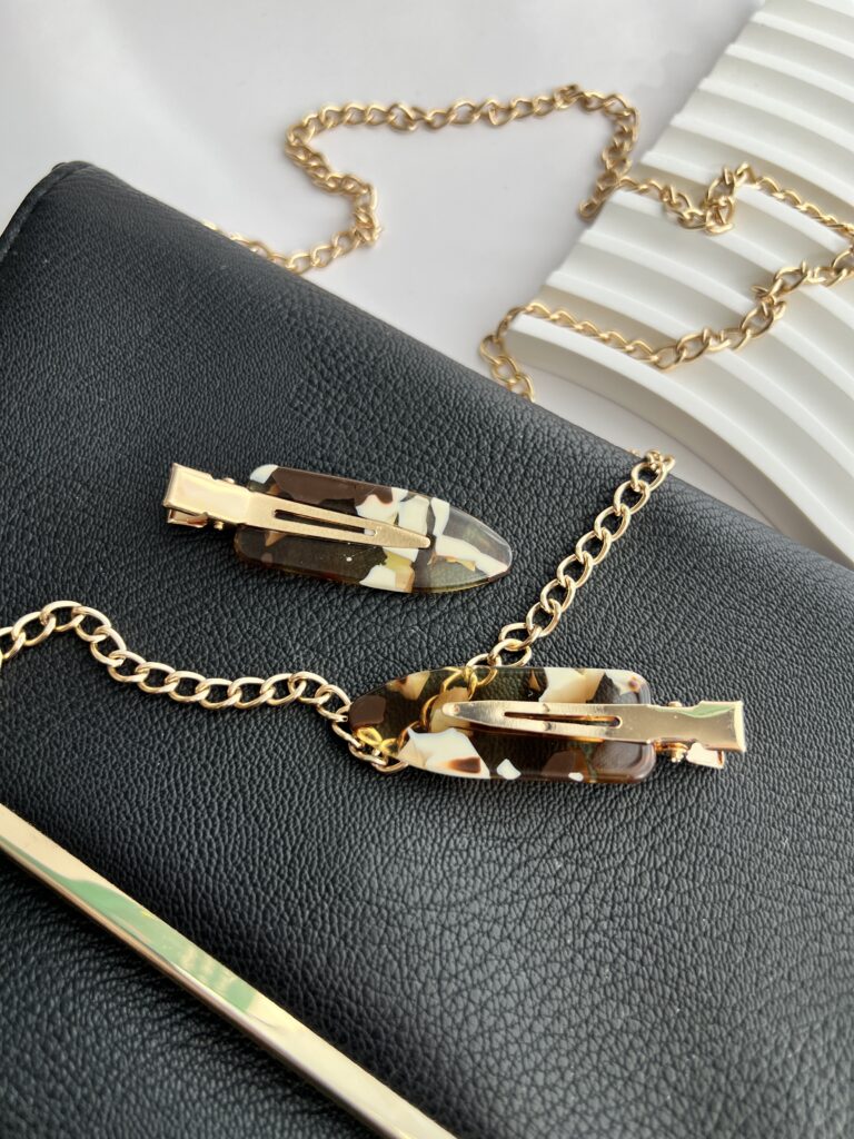 Rudų ir baltų spalvų makiažo plaukų segtukai padėti ant juodos delninukės