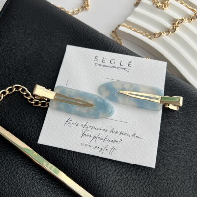 Melsvos spalvos plaukų segtukai įsegti baltoje kortelėje