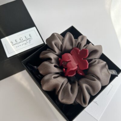 Juodoje dėžutėje šilkinė plaukų gumytė pilkai rusvos spalvos ir raudonos spalvos gėlės formos plaukų segtukas