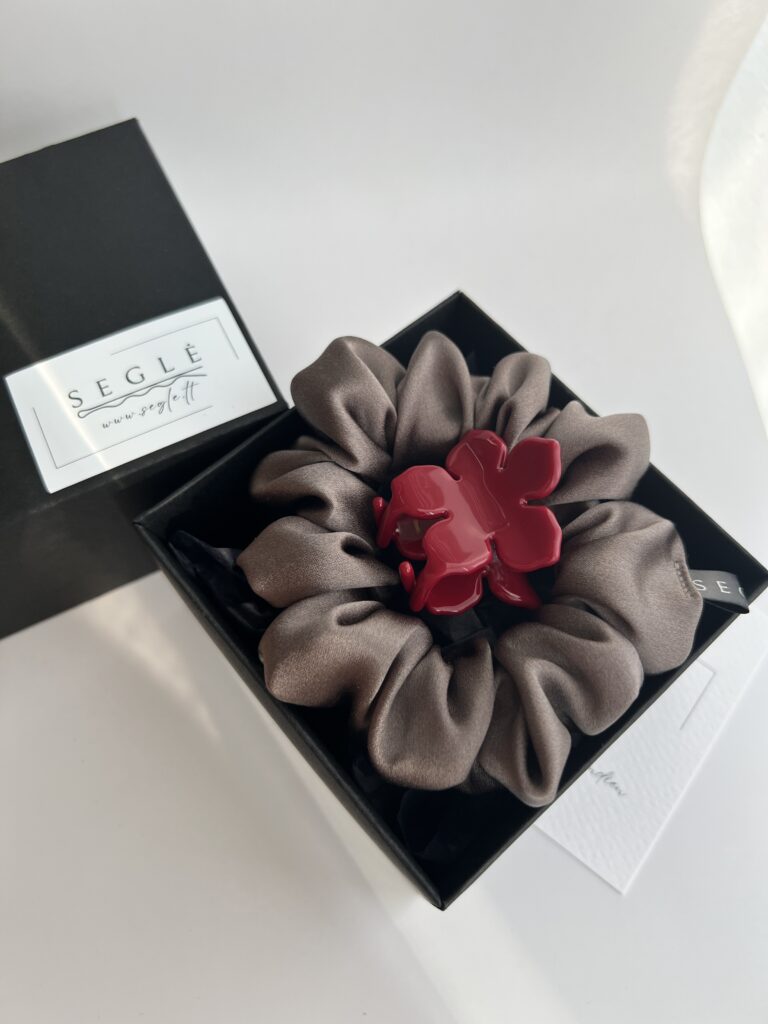 Juodoje dėžutėje šilkinė plaukų gumytė pilkai rusvos spalvos ir raudonos spalvos gėlės formos plaukų segtukas