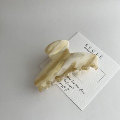 Šviesių karamelinių spalvų plaukų segtukas žnyplės baltame fone