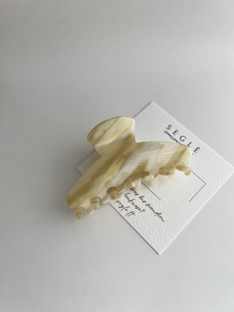 Šviesių karamelinių spalvų plaukų segtukas žnyplės baltame fone