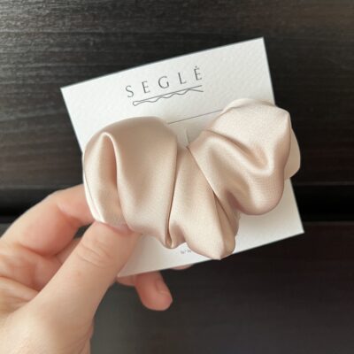 Plaukų segtukas šviesios pudros spalvos pagamintas iš dirbtinio šilko. Segtukas baltoje kortelėje juodame fone