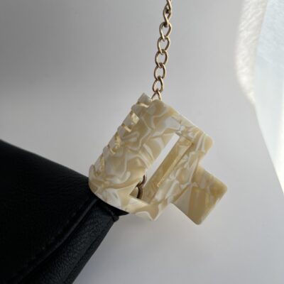 Šviesių baltų ir gelsvų spalvų kvadratinės formos plaukų segtukas žnyplės