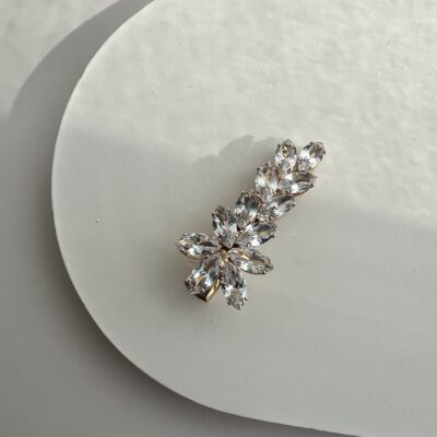 Metalinis aukso spalvos segtukas plaukams dekoruotas blizgančiais cirkoniais. Cirkoniai išdėstyti gėlės forma