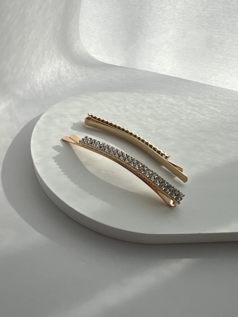 Metaliniai aukso spalvos segtukai dekoruoti skaidriais blizgančiais akmenukais