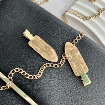 Šviesiai rudos spalvos makiažo plaukų segtukai padėti ant juodos delninukės