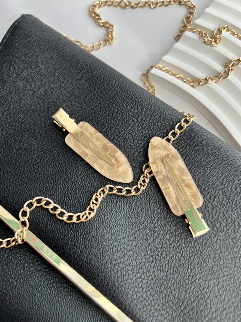 Šviesiai rudos spalvos makiažo plaukų segtukai padėti ant juodos delninukės