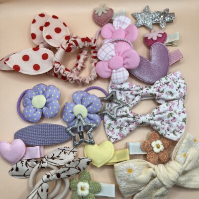 Daug spalvingų plaukų gumyčių ir plaukų segtukų mergaitėms rusvame fone