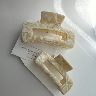 Du plaukų segtukai žnyplės baltame fone. Segtukai baltos ir kreminės spalvos