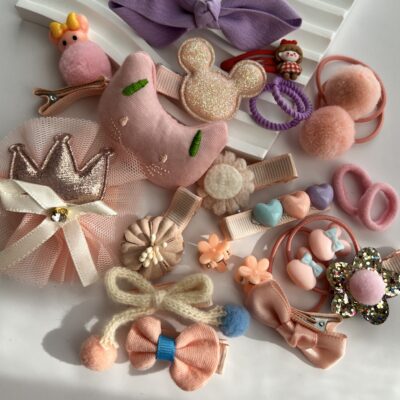 Rausvų spalvų plaukų segtukai ir gumytės baltame fone