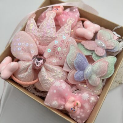 daug žaismingų rausvų plaukų segtukų mergaitėms rudoje dėžutėje