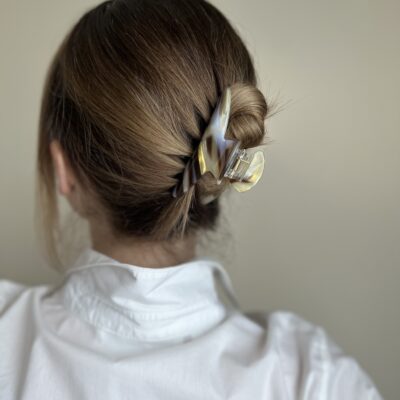 Susegti visi plaukai su plaukų segtuku. Segtukas šviesios rusvos spalvos su rudomis linijomis