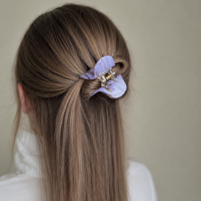 Susegta dalis plaukų su violetinės spalvos plaukų segtuku žnyplėmis. Segtukas nedidelis