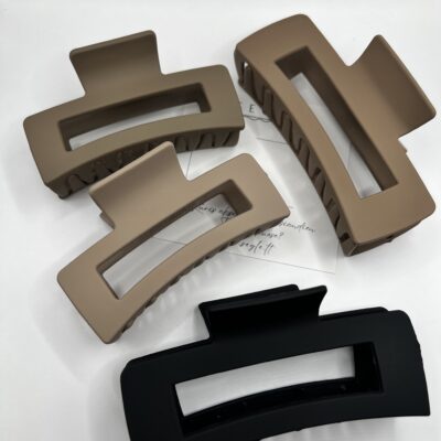 Matiniai keturi plaukų segtukai žnyplės baltame fone. Trys segtukai rudos spalvos ir vienas judos