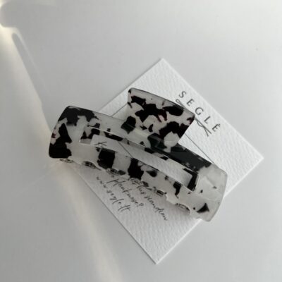 Baltos ir juodos spalvos plaukų segtukas žnyplės baltame fone ant popierinės kortelės