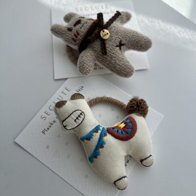 Dvi plaukų gumytės mergaitėms. Viena plaukų gumytė su rudu meškučiu, o kita su balta alpaka.