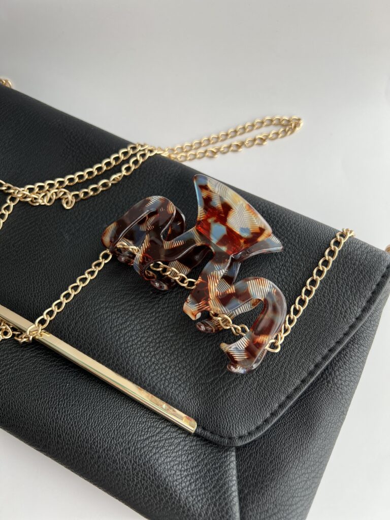 Bangelės formos plaukų segtukas užsegtas ant juodos delninukės