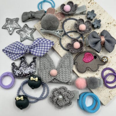 Pilkų spalvų plaukų segtukai ir gumytės mergaitėms baltame fone