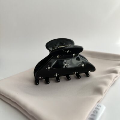 Juodos spalvos vidutinio dydžio plaukų segtukas žnyplės. Segtukas dekoruotas blizgančiais akmenukais