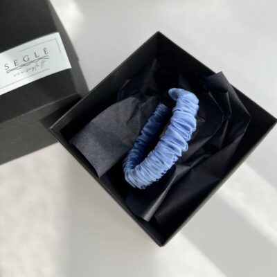 Šviesiai mėlynos spalvos siaura šilkinė plaukų gumytė juodoje dėžutėje