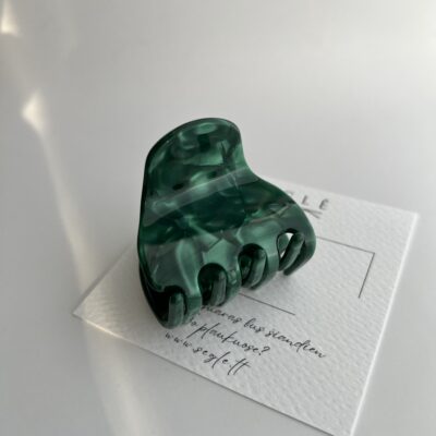 Sodrios žalios spalvos vidutinio dydžio plaukų segtukas žnyplės baltame fone ant popierinės baltos kortelės