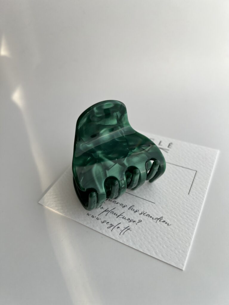 Sodrios žalios spalvos vidutinio dydžio plaukų segtukas žnyplės baltame fone ant popierinės baltos kortelės