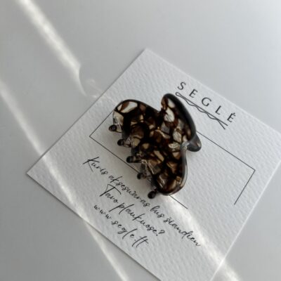 Nedidelis skaidrus plaukų segtukas žnyplės su rudais atspalviais, kurie atrodo lyg kavos burbulai