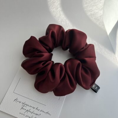 Rubino spalvos šilkinė plaukų gumytė baltame fone