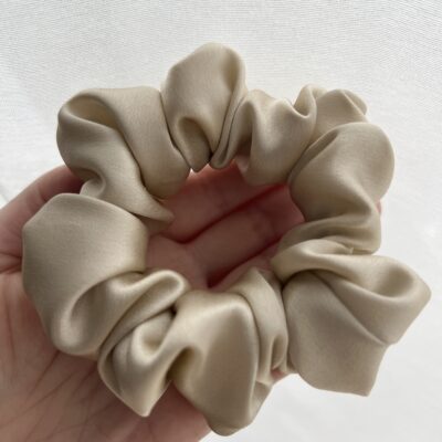 Šampaninės spalvos šilkinė plaukų gumytė ant rankos