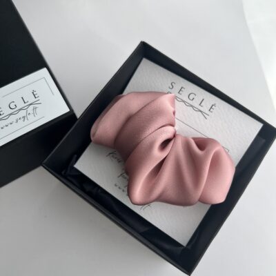 Rausvos spalvos plaukų segtukas, kuris savo dizainu panašus į kruasaną