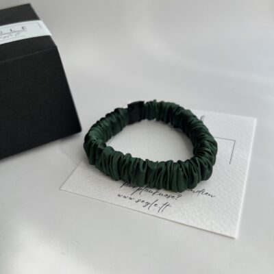 Siaura - mini, žalios spalvos šilkinė gumytė baltame fone šalia juodos dėžutės