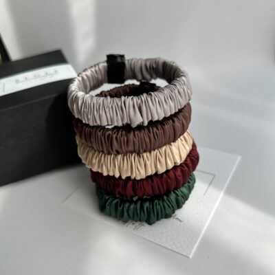 Daug siaurų šilkinių plaukų gumyčių. Gumytės sustatytos bokšteliu, viena ant kitos