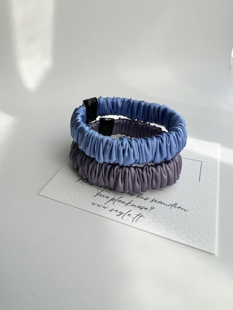 Dvi siauros šilkinės plaukų gumytės baltame fone. Gumytės šviesios levandų ir melsvos spalvos