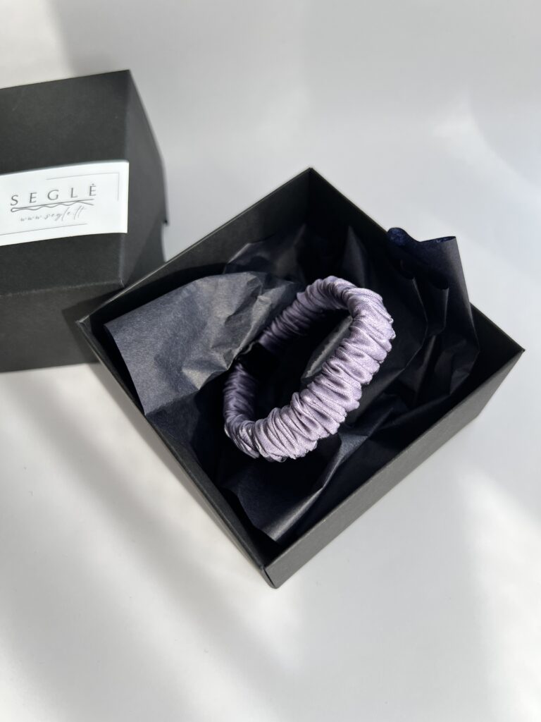 Siaura šilkinė plaukų gumytė. Gumytė šviesios levandų spalvos, juodoje dėžutėje