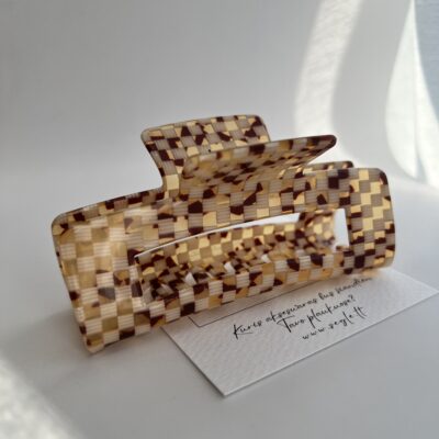 Didelis pailgas plaukų segtukas žnyplės, kurio paviršius atrodo lyg smulkių rusvų spalvų langelių mozaika