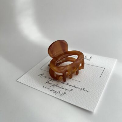 Rudos spalvos nedidelis plaukų segtukas žnyplės baltame fone