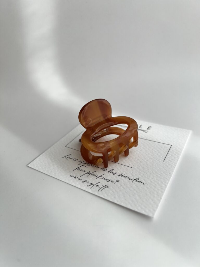 Rudos spalvos nedidelis plaukų segtukas žnyplės baltame fone