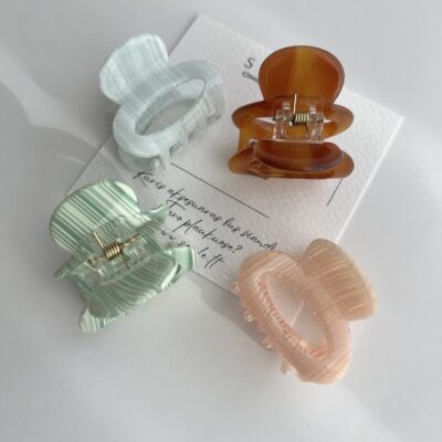 Nedideli, keturių skirtingų spalvų plaukų segtukai baltame fone