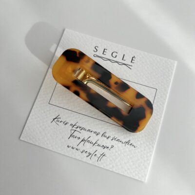 Tamsios karamelinės spalvos plaukų segtukas. Segtuko paviršius plastikinis, užsegimas metalinis.