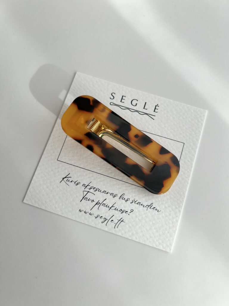 Tamsios karamelinės spalvos plaukų segtukas. Segtuko paviršius plastikinis, užsegimas metalinis.