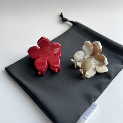 Gėlės formos du nedideli plaukų segtukai ant juodo maišelio