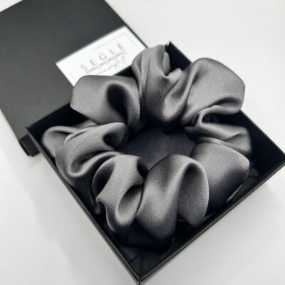 natūralaus šilko klasikinės pilkos spalvos šilinė plaukų gumytė juodoje dėžutėje. Gumytė didesnė