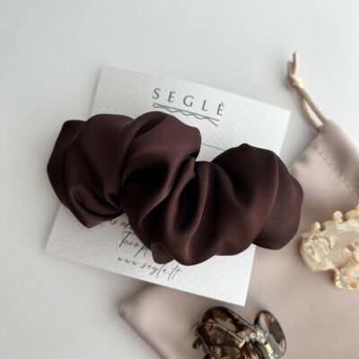 tamsaus šokolado spalvos plaukų segtukas šalia rusvo maišelio ir dviejų nedidelių plaukų segtukų žnyplių