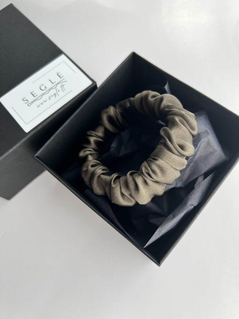 Nedidelė, tamsiai rudos spalvos su chaki atspalviu natūralaus šilko plaukų gumytė juodoje dėžutėje